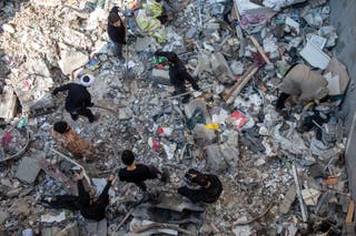 People sift through rubble after a strike in Tehran on Tuesday
